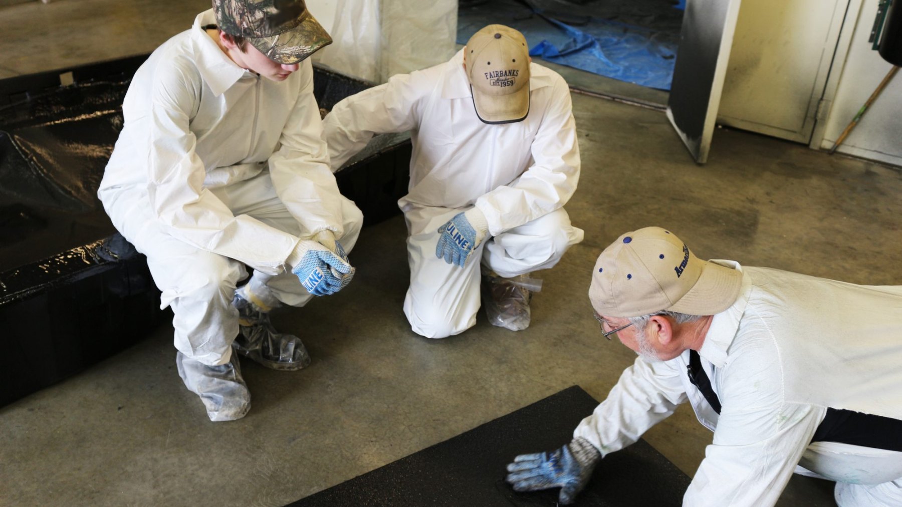 Trainees examining a finished polyurea surface up close during an inspection exercise