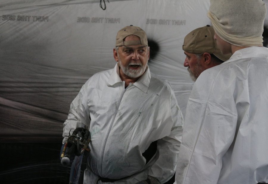 Instructor talking a trainee through gun technique inside the spray booth