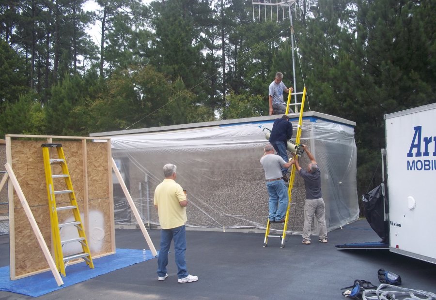 Trainees building a temporary spray enclosure next to the mobile coatings trailer