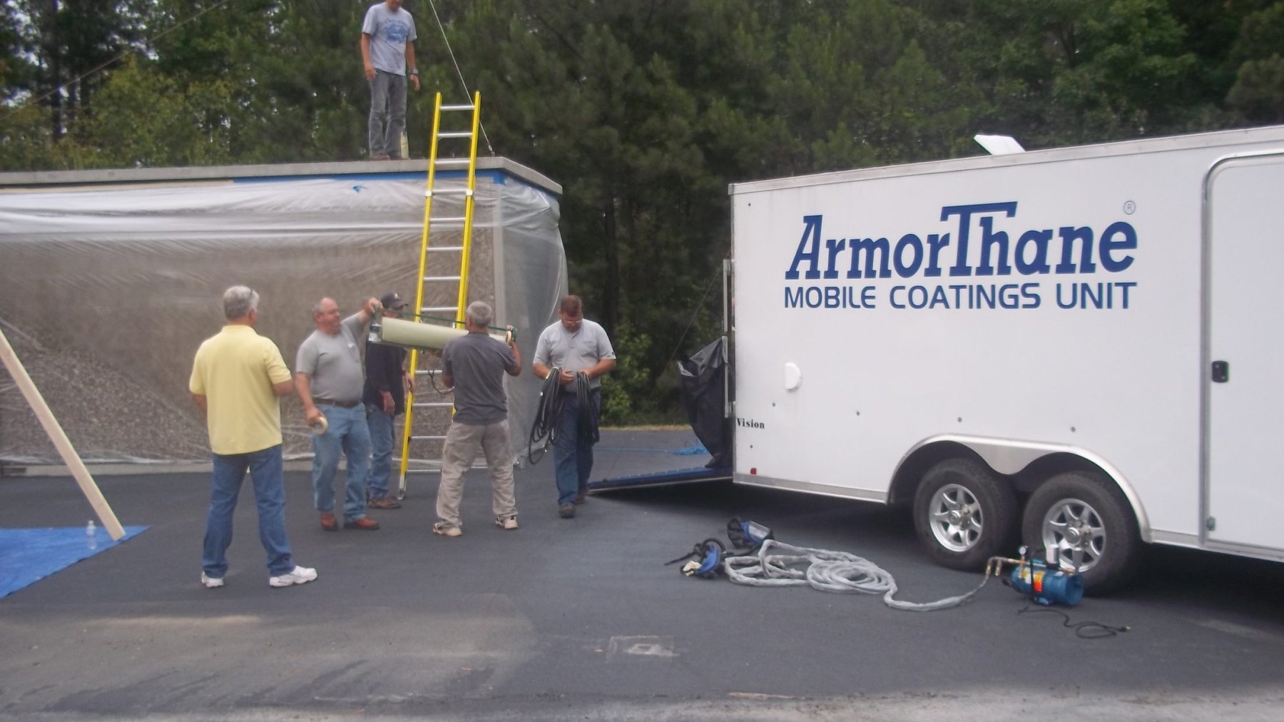 A class gathered around a temporary spray enclosure beside the ArmorThane Mobile Coatings Unit