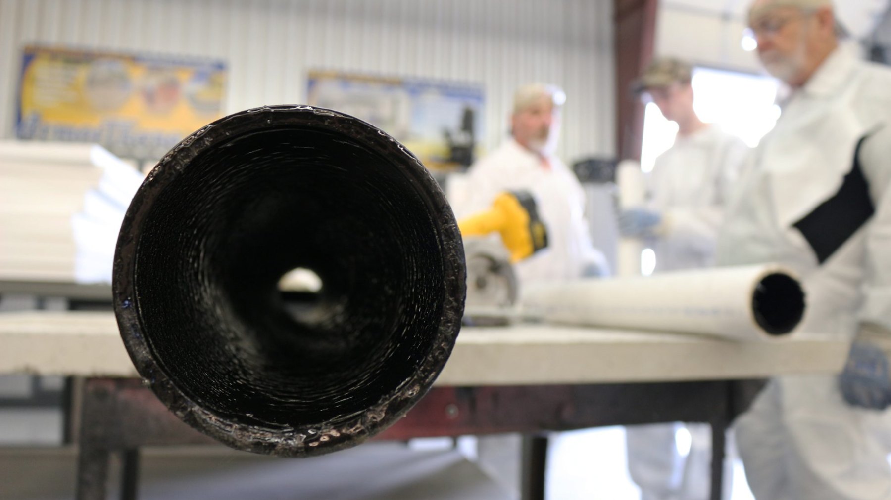 Close view into the open end of a pipe showing a glossy black polyurea lining