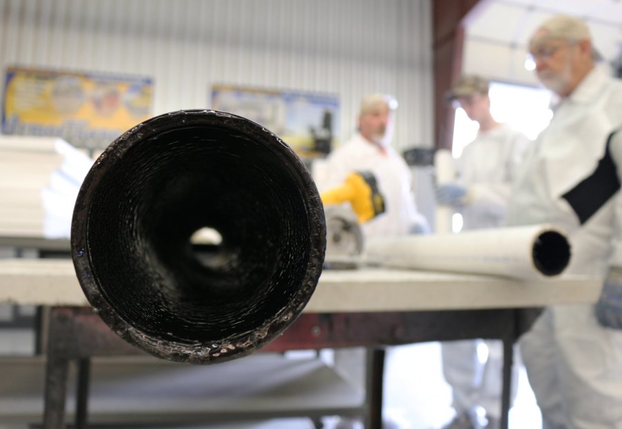 Close view into the open end of a pipe showing a glossy black polyurea lining