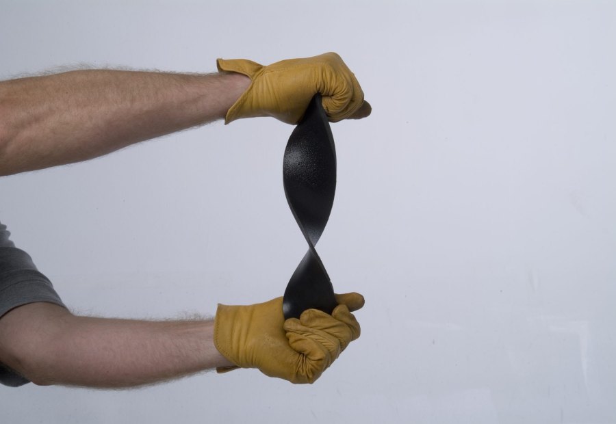 Two gloved hands stretching and twisting a cured polyurea sample to show its elongation