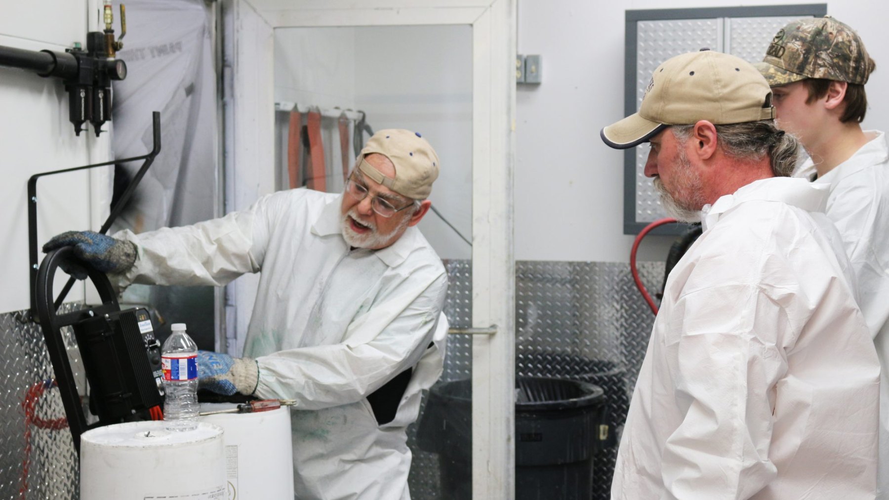 Instructor demonstrating a plural-component proportioner to two trainees