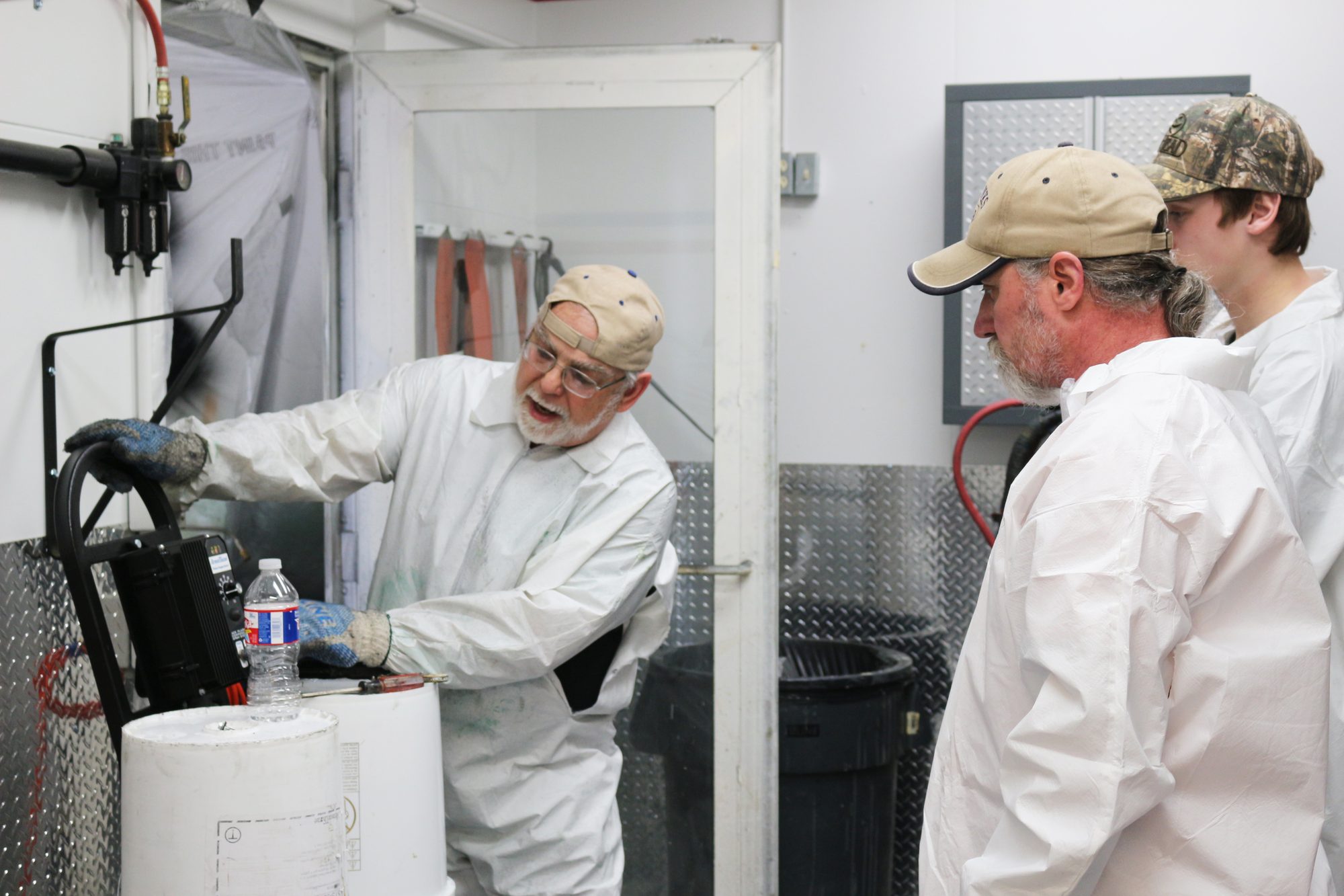 Instructor demonstrating a plural-component proportioner to two trainees