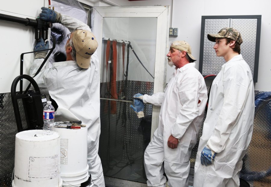 Instructor priming a transfer pump from a material drum while trainees watch